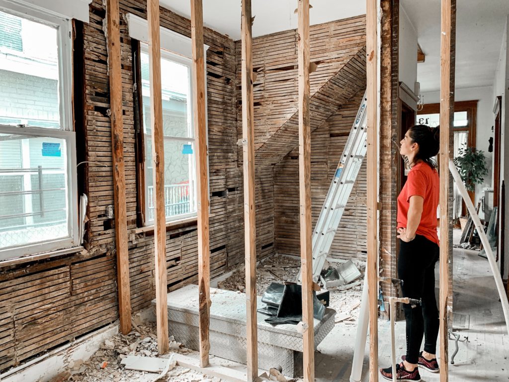 Woman in an orange top looking at her home being renovated