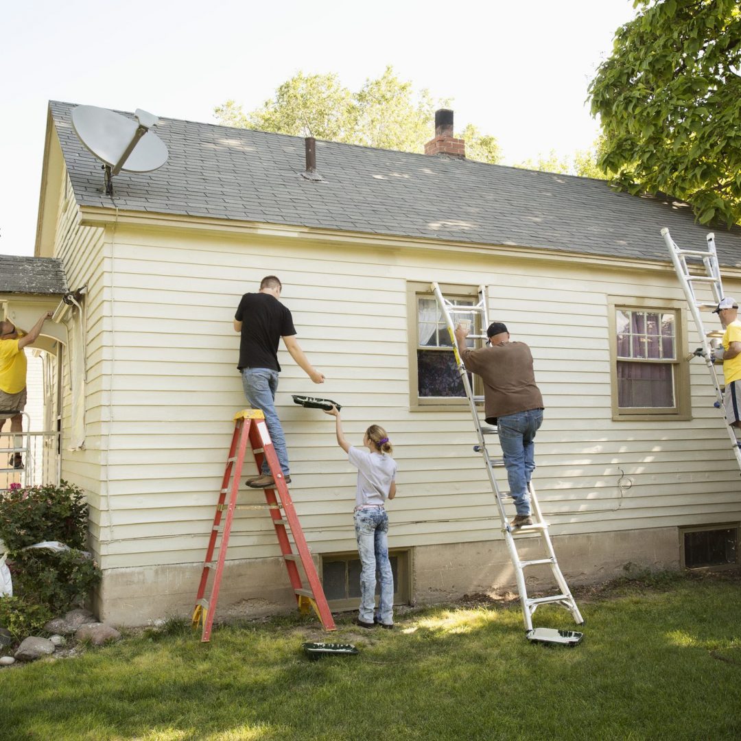 Group of people painting the outside of a house