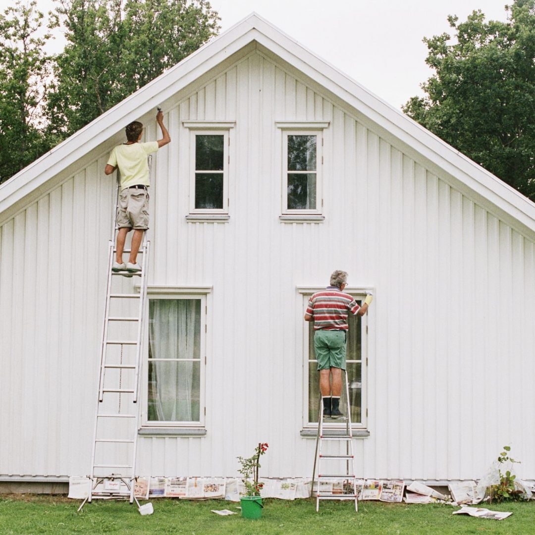 Two men painting the ourside of a house